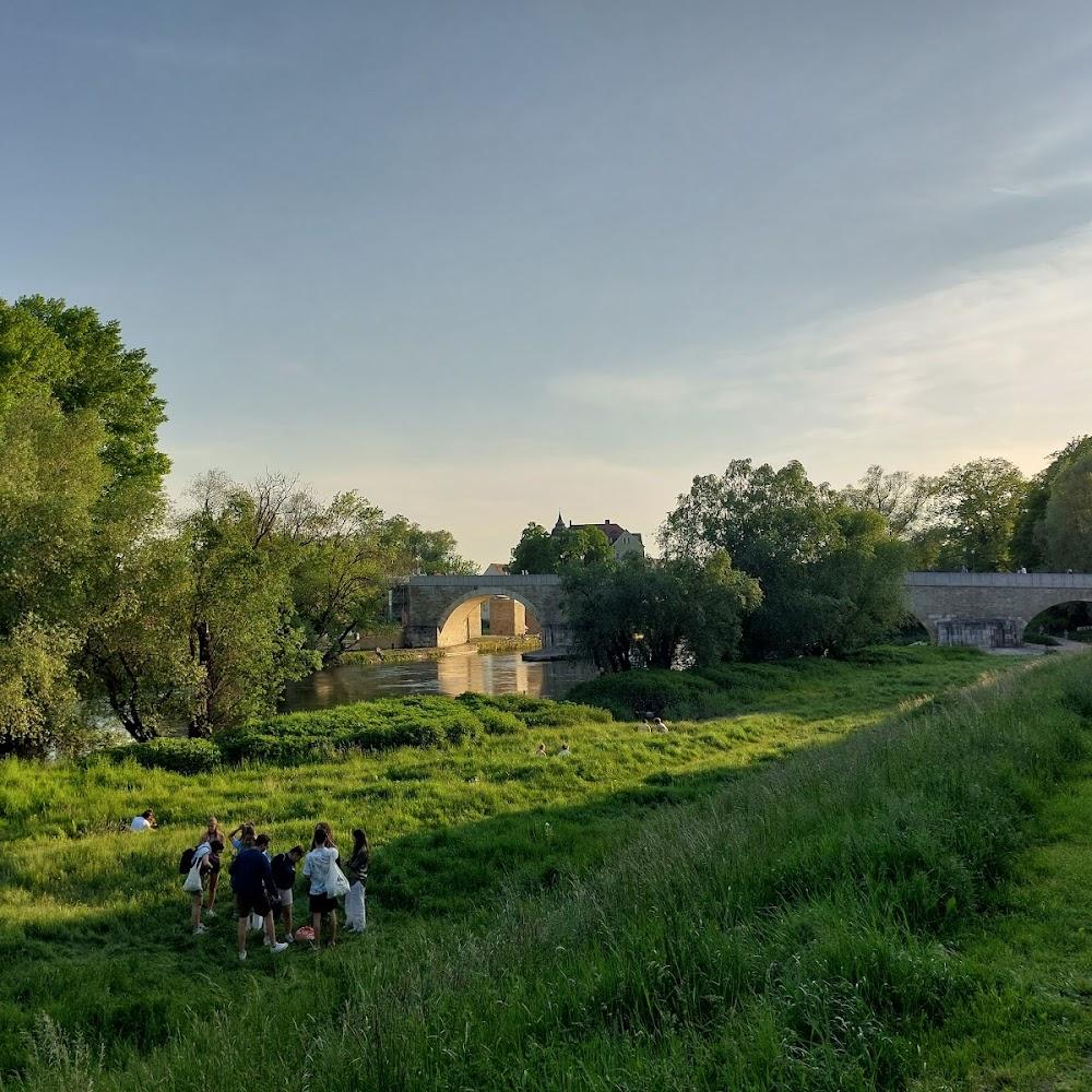 Stone bridge over a river with people on the bank.